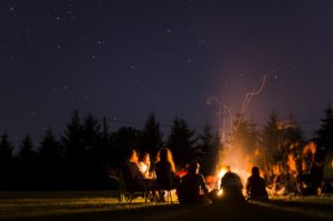 People sitting around a campfire at night.